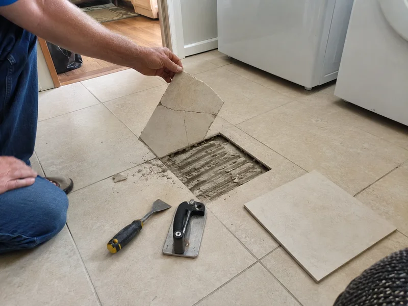 Cracked floor tile being cut out and lifted