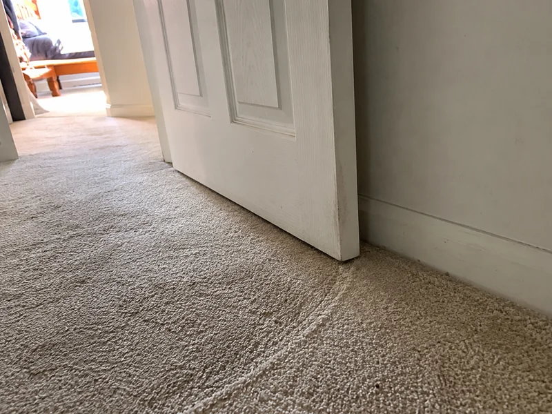 Internal door dragging on the carpet with a worn scuff arc