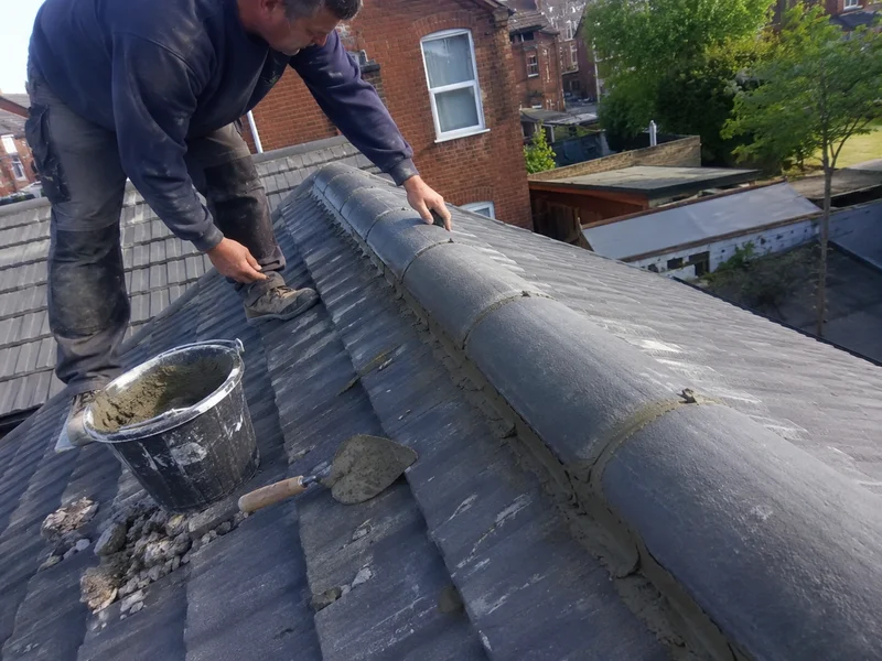 Ridge capping being re-bedded and pointed