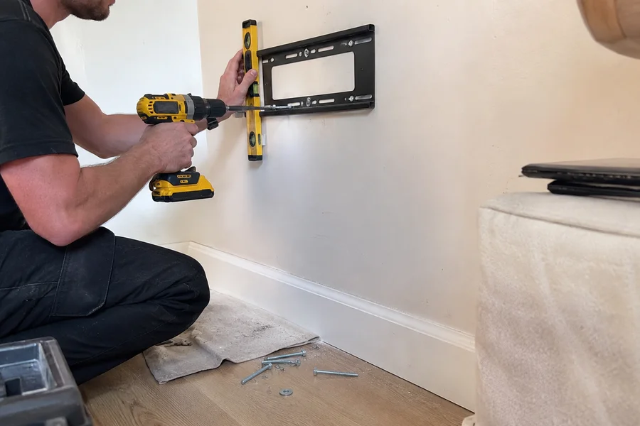 Cavity anchor and stud fixing being driven into plasterboard with a level on the bracket